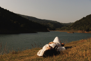 一个人躺在草地上 头靠在别人的头上 在靠近水域的田野中 有湖泊。