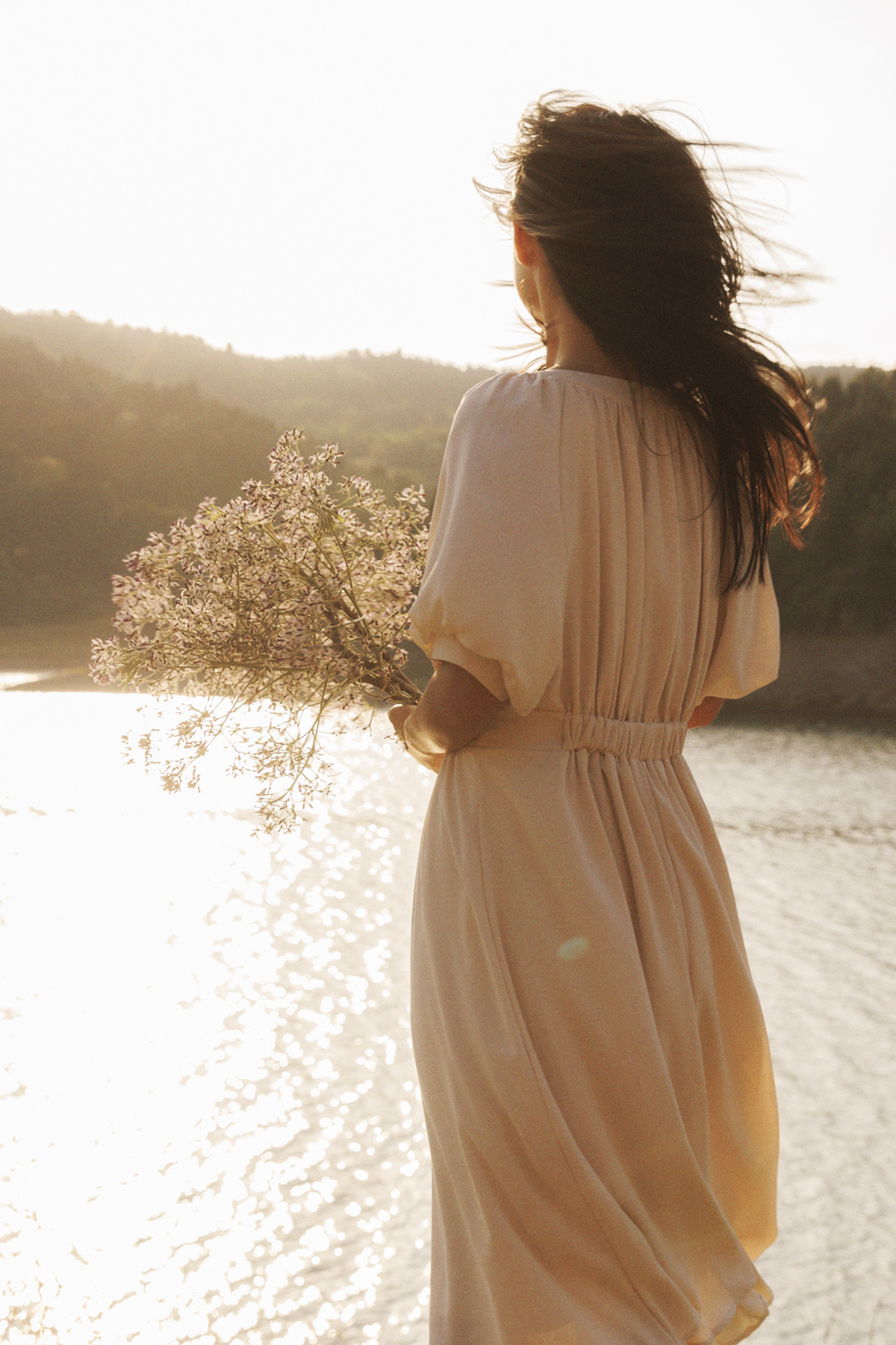 一位美丽的年轻女子穿着白色连衣裙站在水边
