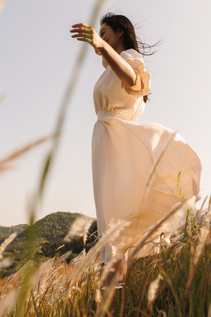 一位穿着白色连衣裙的年轻女子站在草地上