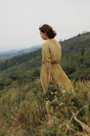 一位穿着黄色连衣裙的女士站在花丛中