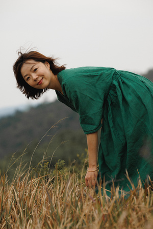 一位穿着绿裙子的年轻女子站在一片高草地上