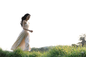 一位美丽的年轻女子穿着一件白色连衣裙站在一个草地上