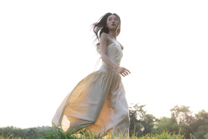 一位美丽的年轻女子穿着一件白色连衣裙站在田野中