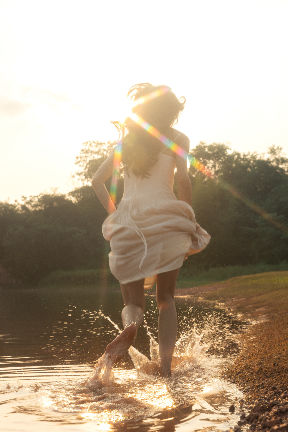 一位穿着白色连衣裙的年轻女子在夕阳西下时跳入湖中的一个水体。