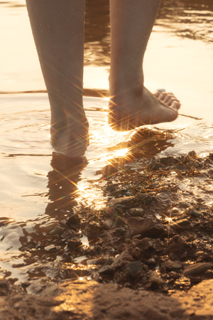 一个光着脚站在泥浆和水坑中的女人 背后是太阳。