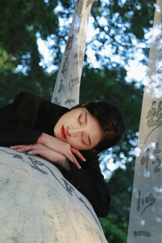 一位年轻女子在背景中有树木的岩石上摆姿势