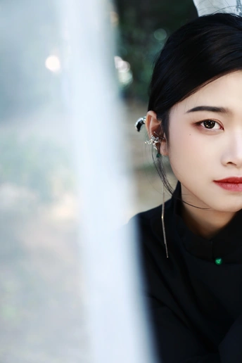 一位戴耳环的女士站在窗前