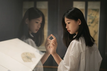 一位年轻女子正拿着手机看着几箱白纸