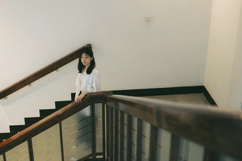 站在一扇白色楼梯顶端的一个年轻女子 旁边还有一些楼梯。