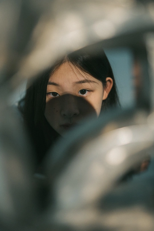 一位年轻女子通过水龙头看着镜子里的自己