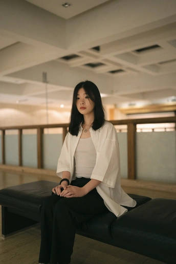 一位女性坐在黑色长凳上 在一个房间里。