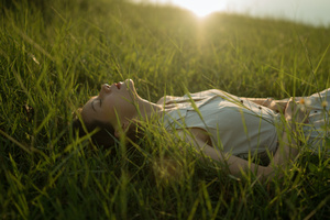 一个年轻女子躺在绿草茵茵的草地上 草丛高过她的头顶。