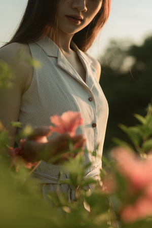 一位年轻女子站在粉红色花朵的田野中的人物肖像