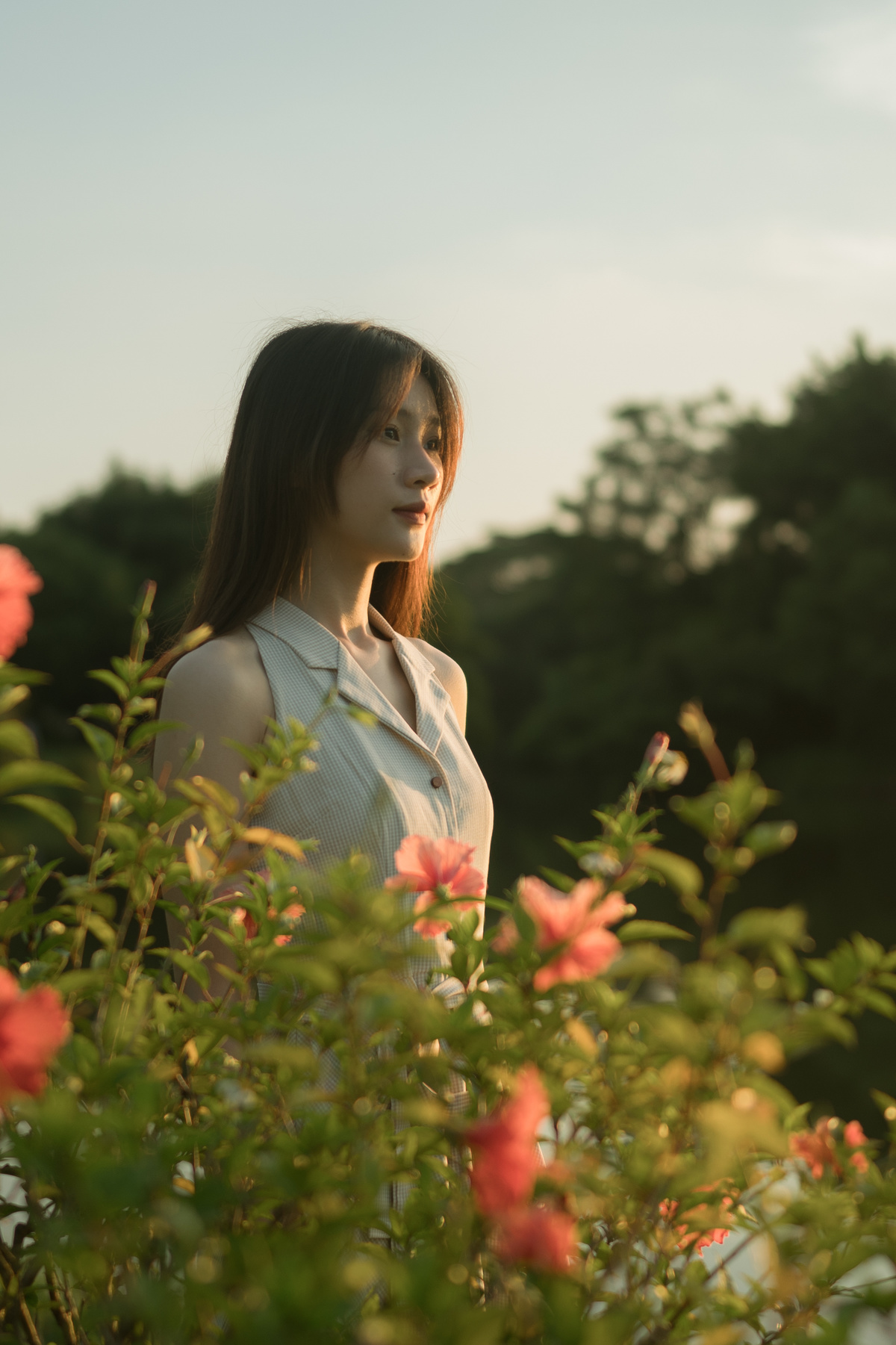 一位年轻女子站在一片红花和灌木丛中