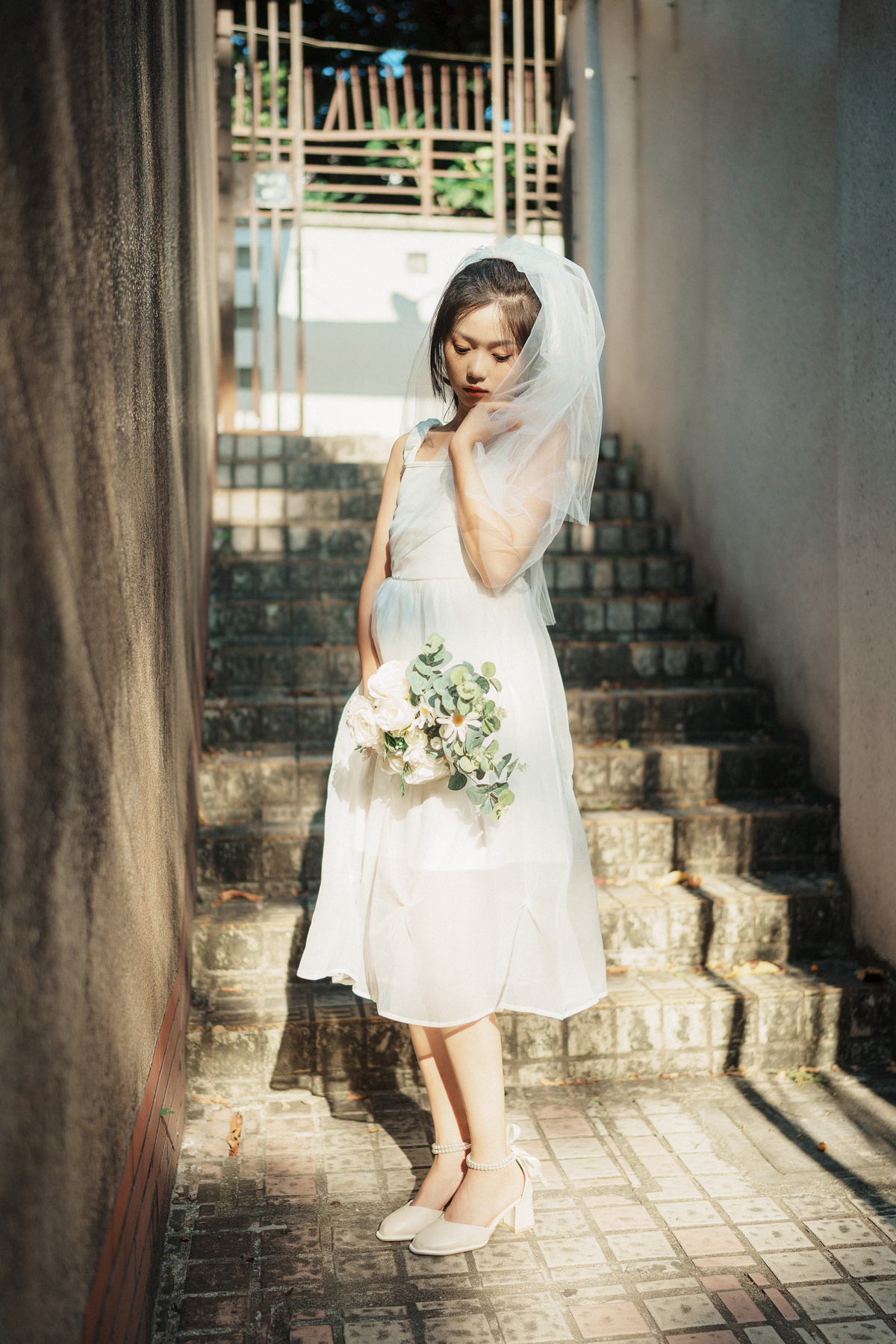 一个穿着白色连衣裙和面纱的年轻女子手拿花束走在婚礼的楼梯上