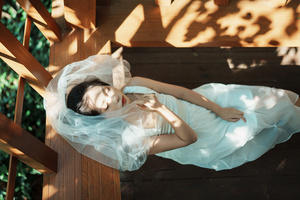 一个穿着蓝色连衣裙的年轻女子躺在木质树屋上