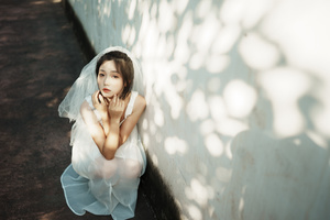 一位穿着蓝色婚纱的年轻女子坐在白色墙壁上