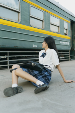 一位年轻女子坐在火车旁边
