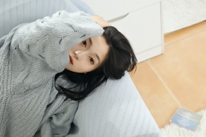 一个女性坐在沙发上 脸上戴着毛衣 躺在地上。
