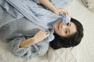一个年轻女子裹着一条蓝色毛毯躺在床上