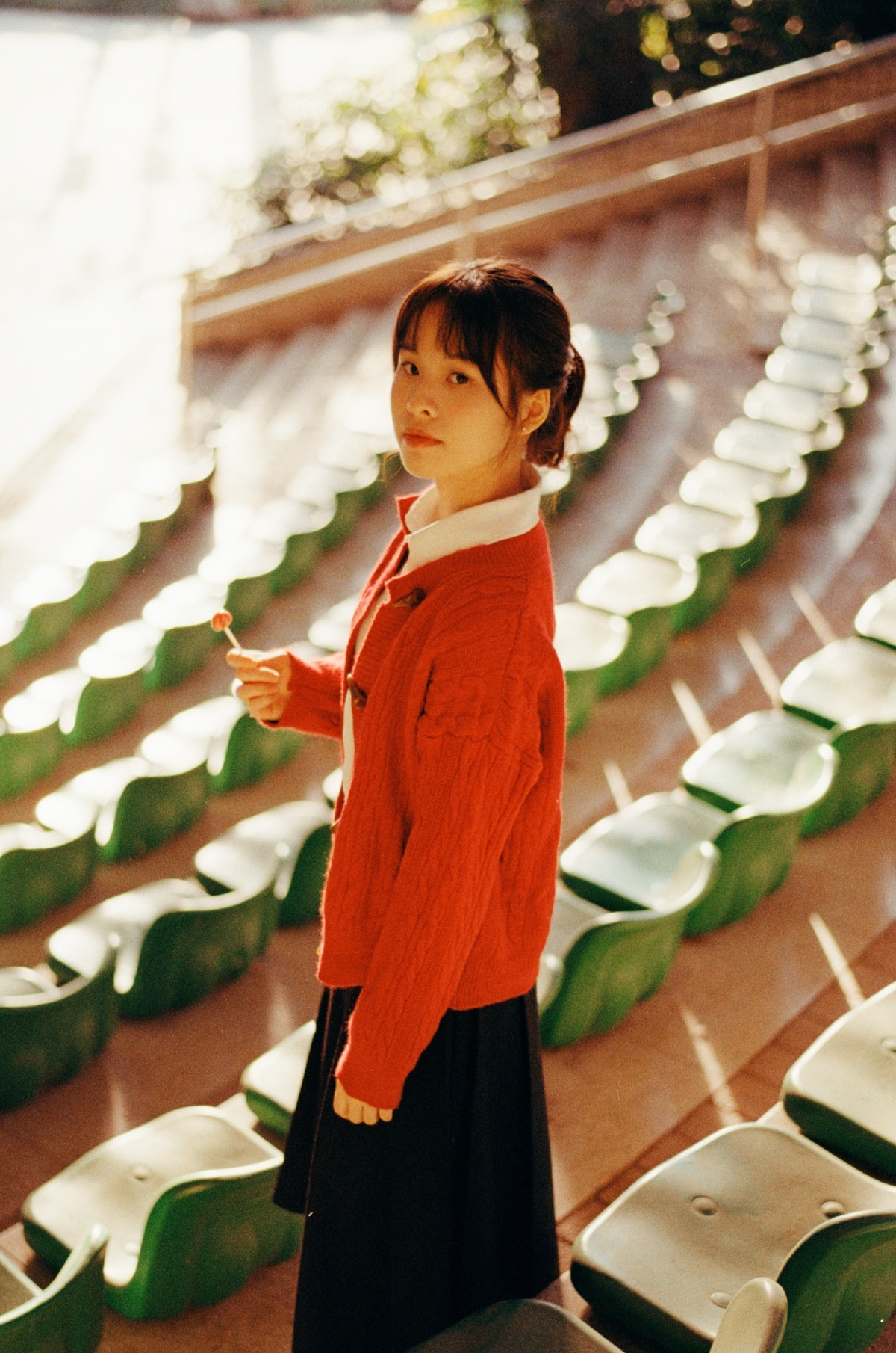 一位穿着橙色毛衣的年轻女子站在空座位前