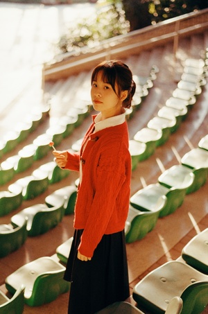 一位穿着橙色毛衣的年轻女子站在空座位前