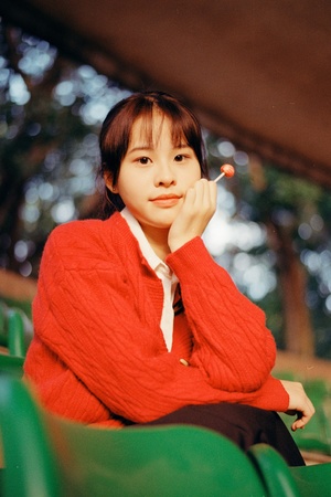 一个穿着红毛衣的年轻女子坐在外面抽烟。