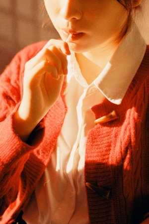 一个小女孩穿着红色的毛衣 用手吃饭。