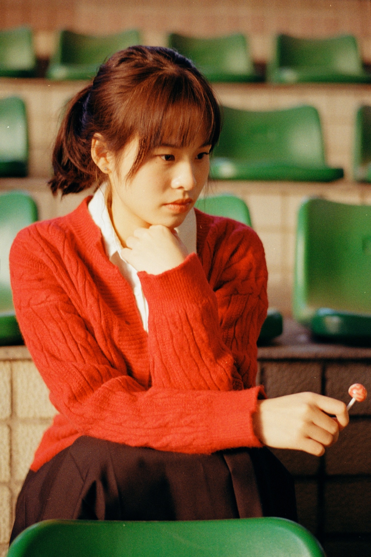 一个穿着红毛衣的年轻女子坐在绿色椅子上