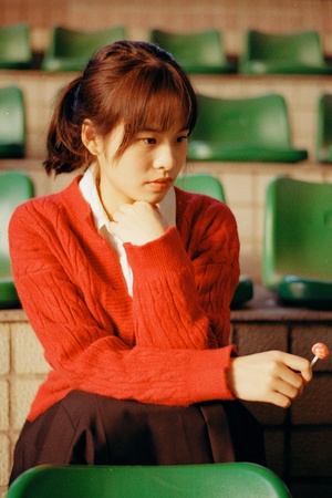 一个穿着红毛衣的年轻女子坐在绿色椅子上