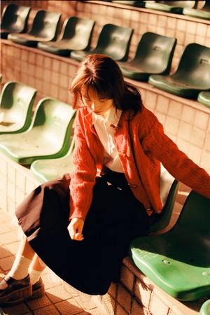 一位年轻女子坐在空座位前面的绿色椅子上