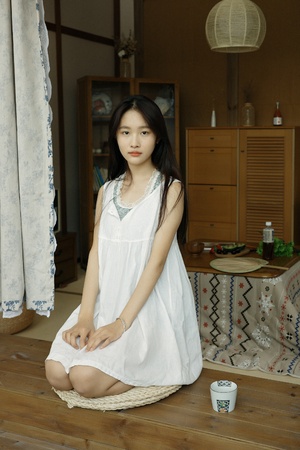 一个穿着白裙子的年轻女孩坐在房间的地板上