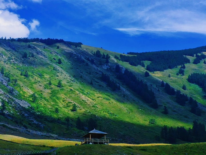 山谷中的绿色山丘和蔚蓝天空下的小屋