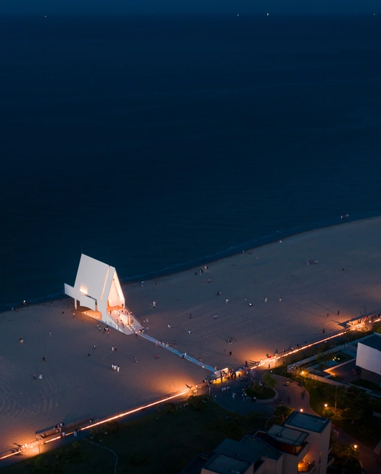 黄昏时海滩的鸟瞰图 白色的灯光和水中的人