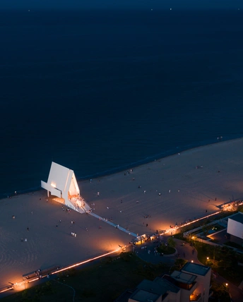 黄昏时海滩的鸟瞰图 白色的灯光和水中的人