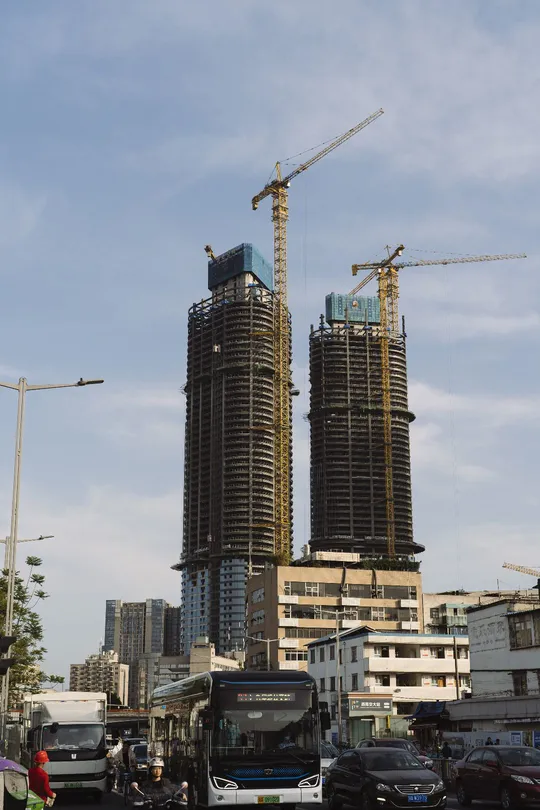 繁忙的街道上有汽车和一辆正在施工中的高楼大厦前面的公交车。