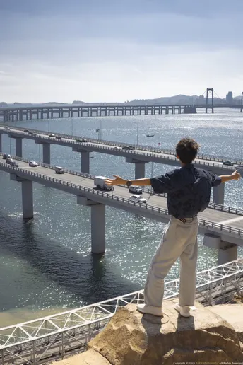 站在岩石上 眺望水面上的一个人