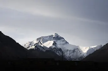 雪覆盖的山脉 太阳低垂在天空中