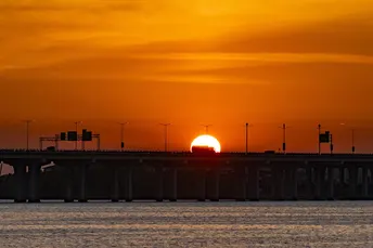 夕阳下的水域 前景中有桥。