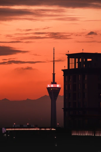 太阳落在一座城市的上空 前景是一座高塔 背景是群山