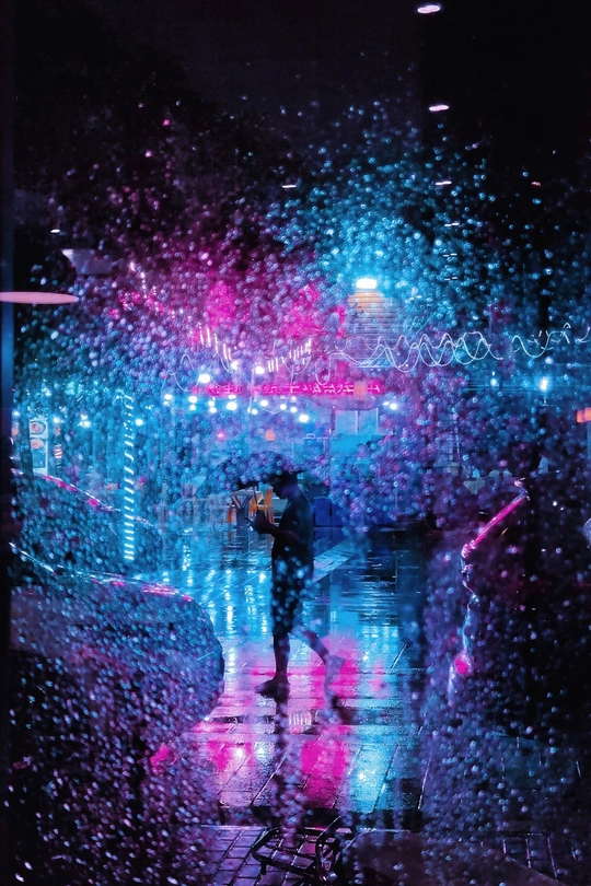 一个蓝色光的雨夜 几个人打着雨伞在雨中行走