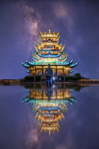 夜晚日本佛塔前站立的男人在水中的倒影