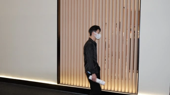 一个戴黑色面具的年轻人走过一扇白色的门