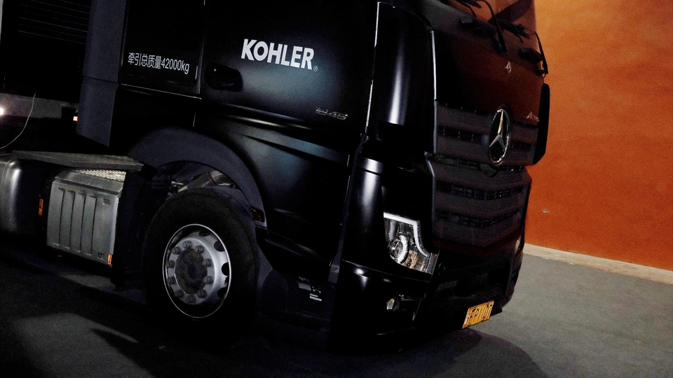 一辆黑色卡车停在旁边有一面橙色墙壁的建筑物里。