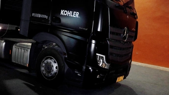 一辆黑色卡车停在旁边有一面橙色墙壁的建筑物里。