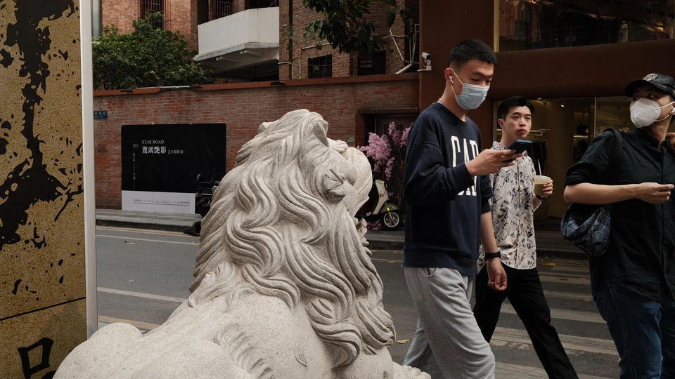 一个戴面具的人在人行道上站在一尊白狮子雕像旁边 人们路过。