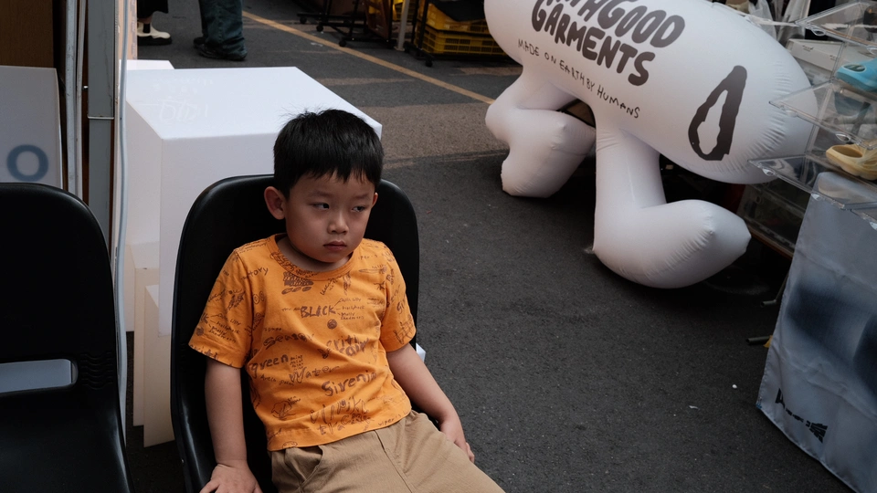 一个穿着橙色衬衫的小男孩坐在一个小椅子上