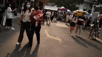 一个人戴着面具走在大街上 周围有一群人围观。