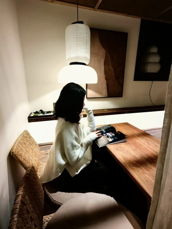 一个人坐在桌子上 房间里有灯和笔记本电脑在桌子上。