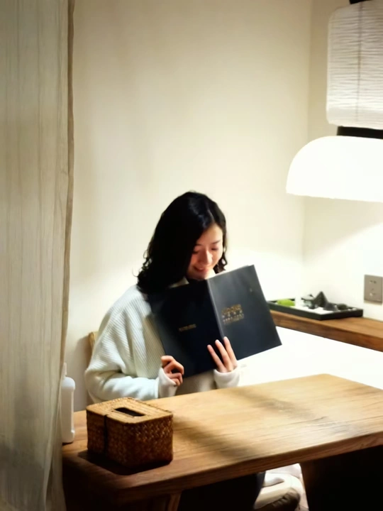 一个年轻女子坐在木制桌子旁读书